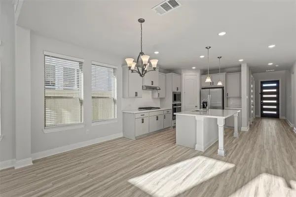 a large white kitchen with a large window a oven and white cabinets