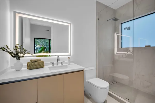 a bathroom with a granite countertop sink toilet and mirror