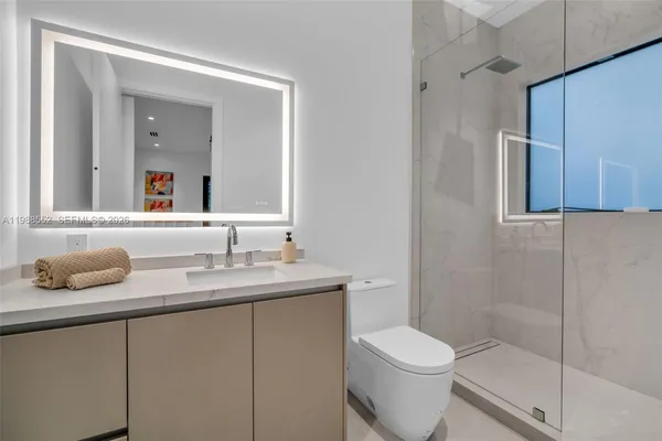 a bathroom with a granite countertop toilet sink and mirror