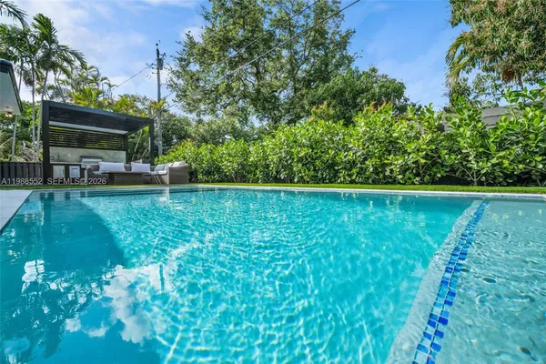 a large room with stainless steel appliances granite countertop couches a barbecue grill and a fireplace with outer view