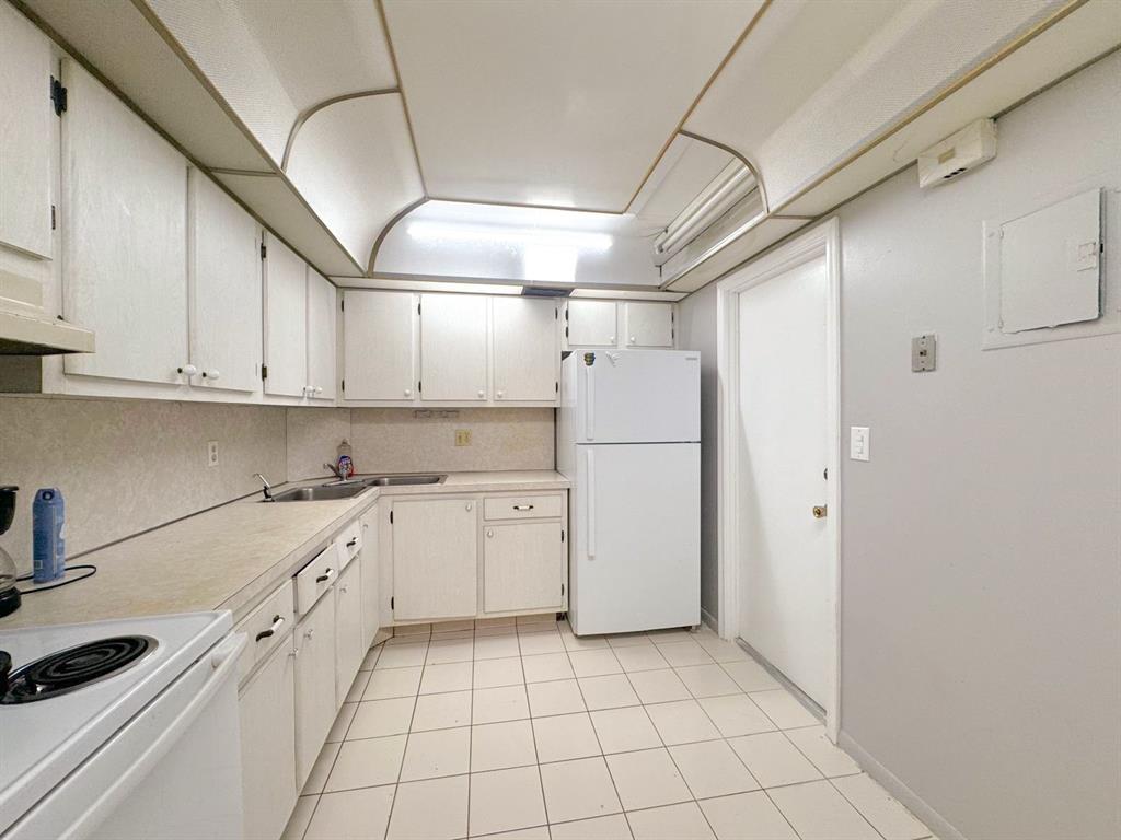 12 Northeast 19th Court, Unit 204A Wilton Manors, FL 33305 - Photo 12 of 21 a kitchen with white cabinets and white appliances
