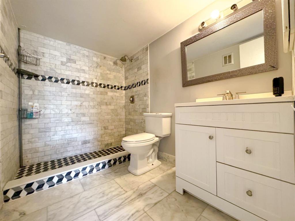 12 Northeast 19th Court, Unit 204A Wilton Manors, FL 33305 - Photo 7 of 21 a bathroom with a granite countertop toilet sink and mirror