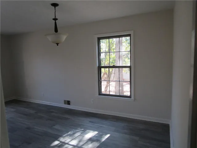 an empty room with wooden floor cabinet and windows