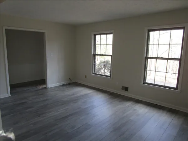 an empty room with wooden floor and windows