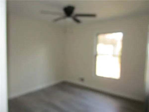 an empty room with wooden floor and a ceiling fan