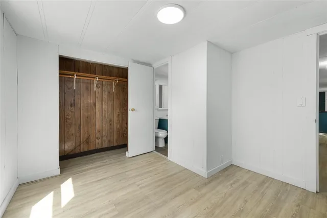 a view of an empty room with wooden floor and closet