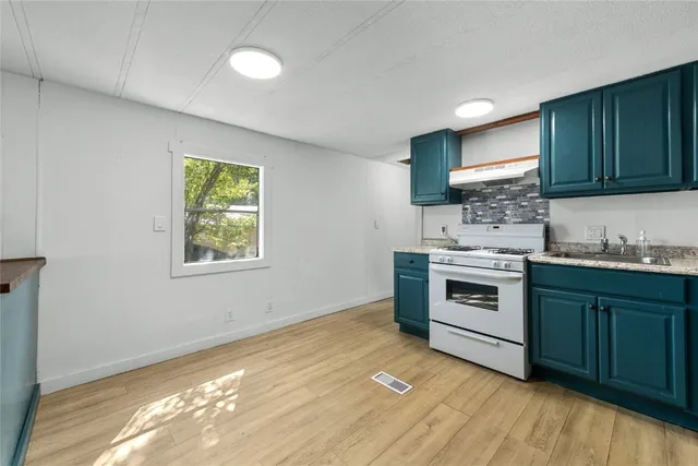 a kitchen with granite countertop a stove a sink and a microwave