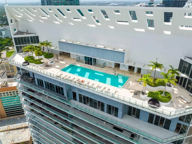 a large white building with a swimming pool and outdoor seating