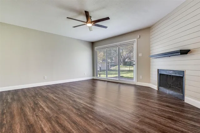 an empty room with wooden floor fireplace and windows