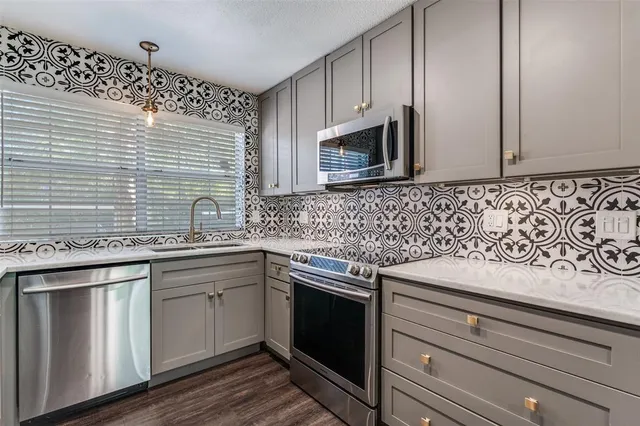 a kitchen with stainless steel appliances granite countertop white cabinets sink and microwave