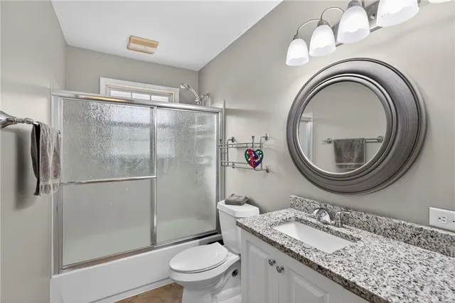 a bathroom with a granite countertop sink a mirror and a toilet