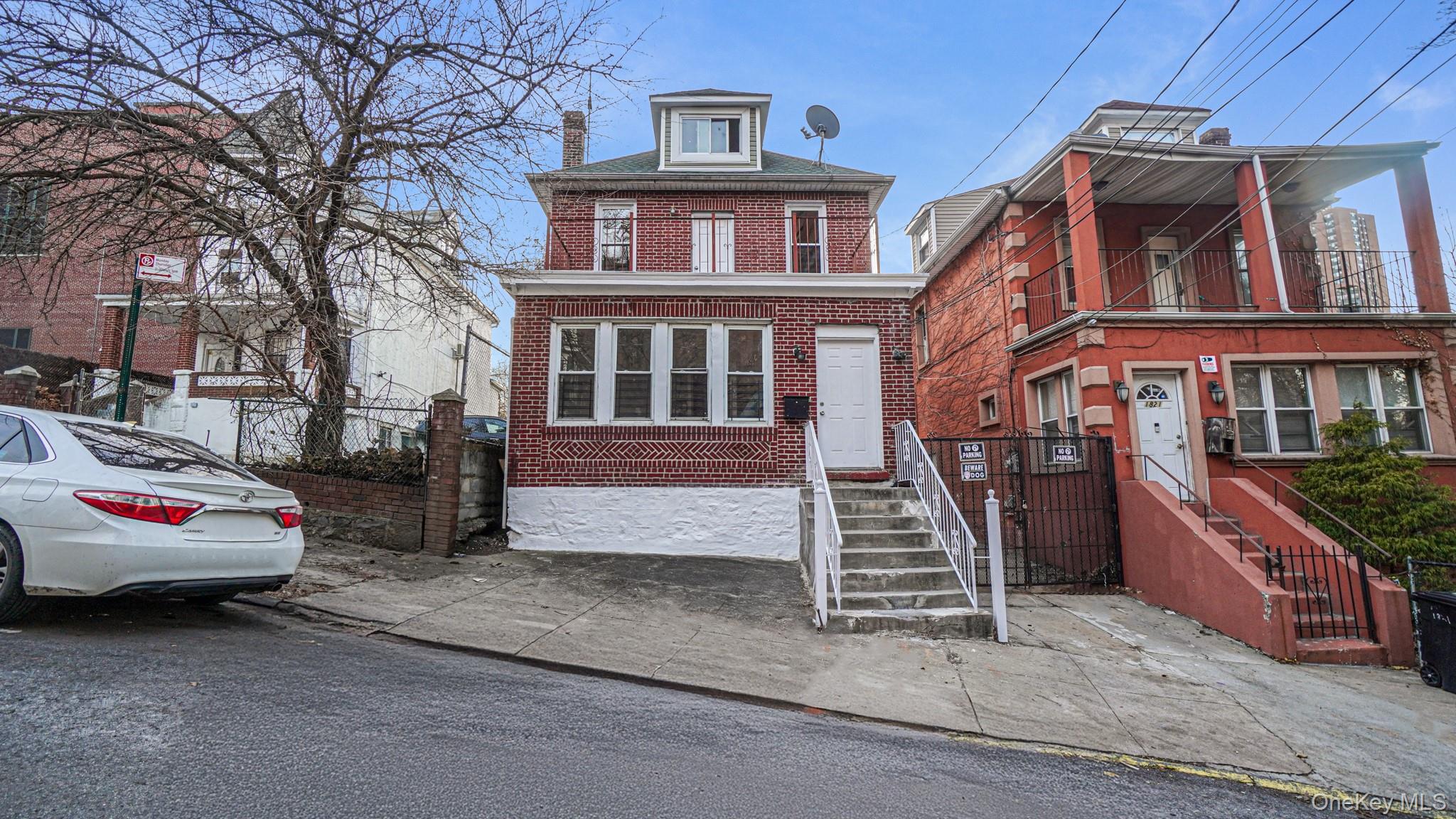 View of front facade featuring brick siding, a balcony, and a chimney