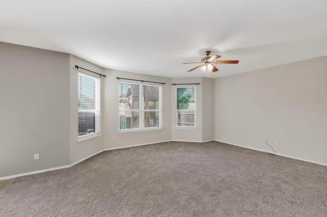 an empty room with chandelier fan and windows