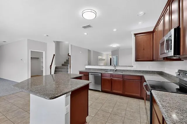 a kitchen with stainless steel appliances granite countertop a sink counter space and a refrigerator