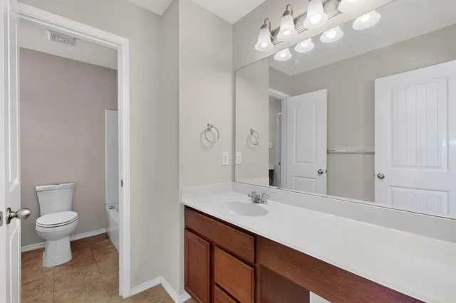 a bathroom with a sink a toilet and a large mirror