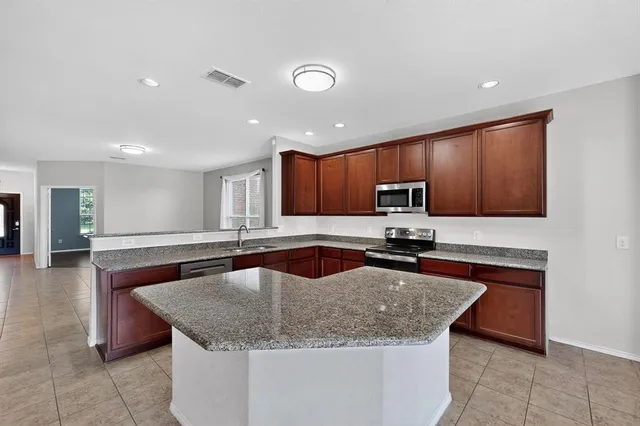 a kitchen with stainless steel appliances granite countertop a sink a stove a microwave and island