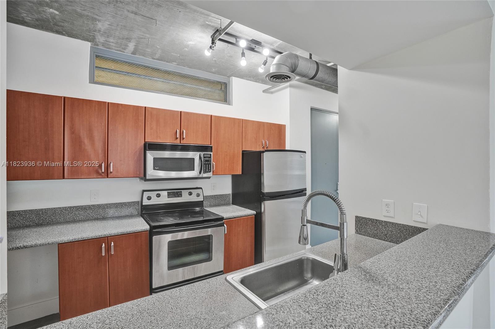 455 Northeast 25th Street, Unit 609 Miami, FL 33137 - Photo 7 of 27 a kitchen with granite countertop a stove and a microwave