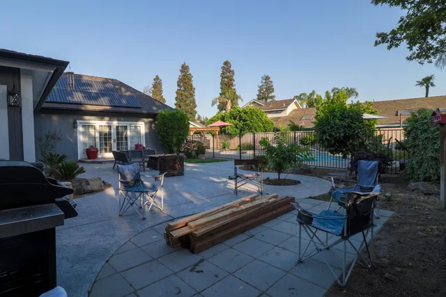 a view of a patio with table and chairs potted plants and a large tree