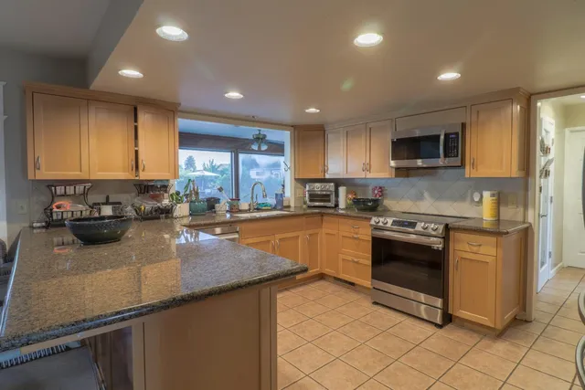 a kitchen with stainless steel appliances granite countertop a stove a sink a microwave and a refrigerator