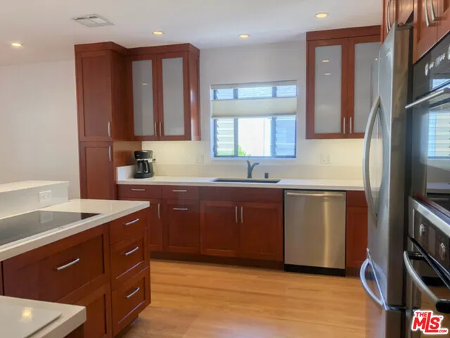 a kitchen with granite countertop a sink cabinets and wooden floor
