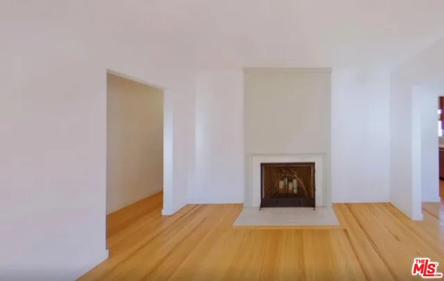 a view of empty room with wooden floor and fireplace