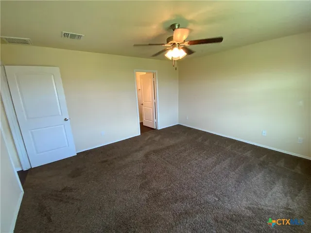 an empty room with a chandelier fan and glass door