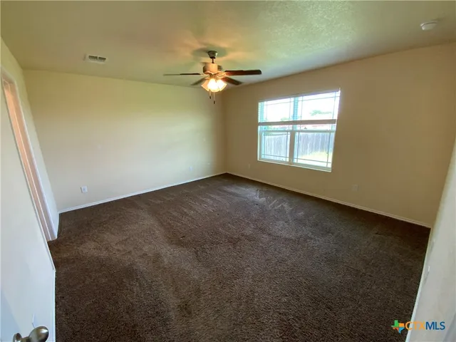 an empty room with windows and fan