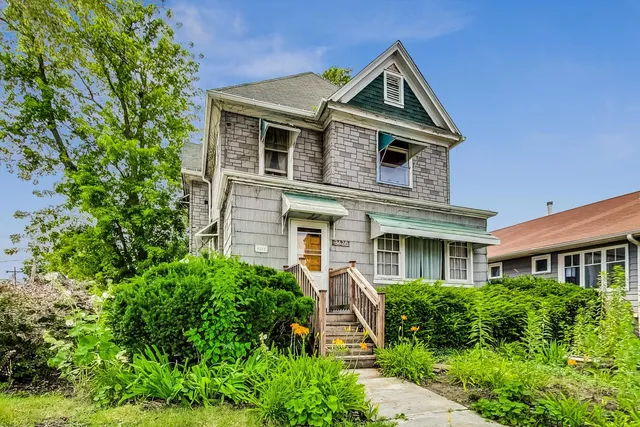 a front view of a house with a yard and potted plants