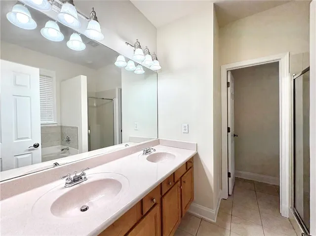a spacious bathroom with a double vanity sink a mirror and a shower