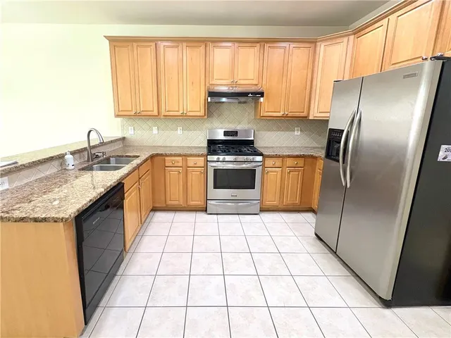 a kitchen with stainless steel appliances granite countertop a stove a sink and a refrigerator