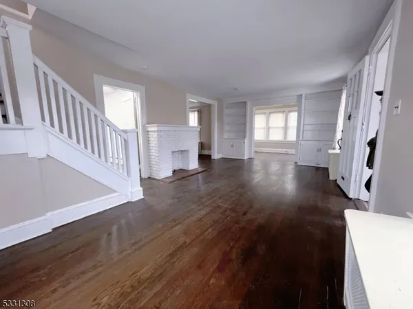 a view of a big room with wooden floor and windows