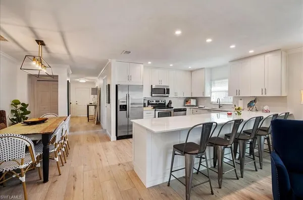 a kitchen with stainless steel appliances kitchen island granite countertop a table chairs and a refrigerator