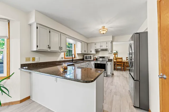a kitchen with stainless steel appliances granite countertop a sink a stove and a refrigerator