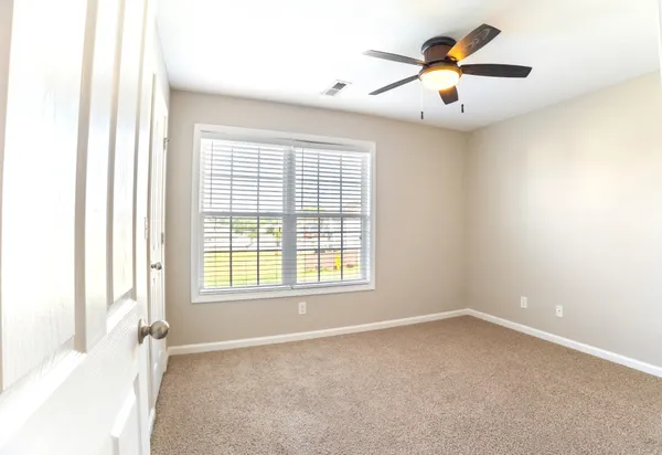 an empty room with a window and a ceiling fan