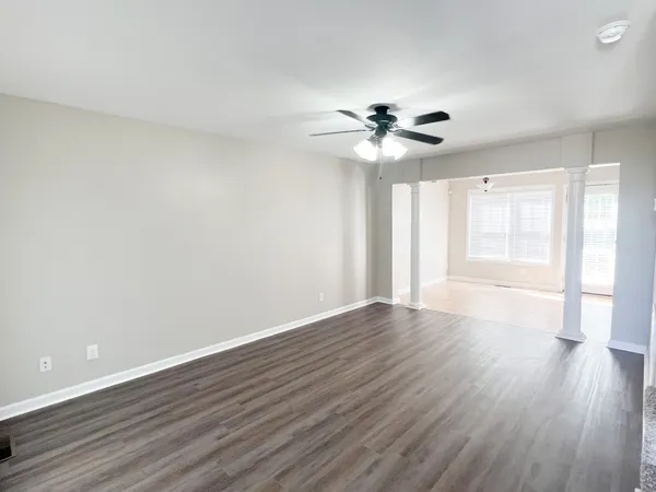 a view of an empty room with wooden floor and a window