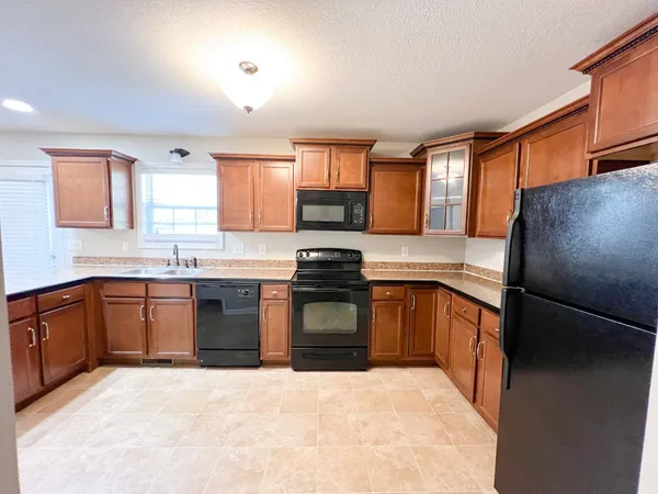 a kitchen with granite countertop a refrigerator stove top oven and sink