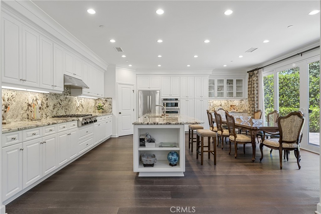 45 Triana Irvine, CA 92618 - Photo 14 of 39 a kitchen with stainless steel appliances kitchen island granite countertop a stove top oven a sink dishwasher a dining table and chairs with wooden floor