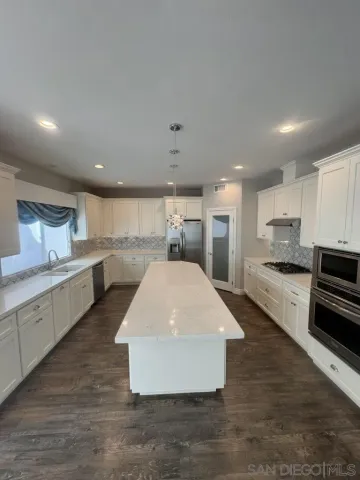 a large kitchen with stainless steel appliances lots of counter space and wooden floor