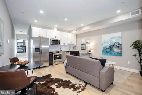 a living room with stainless steel appliances furniture and a view of kitchen