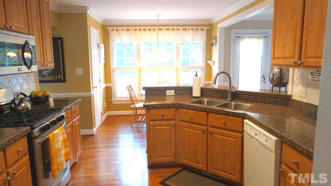 9209 Dawnshire Road Raleigh, NC 27615 - Photo 7 of 25 Bright, Sunny, Open Kitchen, with Granite, new 42" doors, hardwood floors, tile backsplash, stainless steel gas stove, built-in microwave, undermount sink, pull-out faucet, chair rail, and a bar top