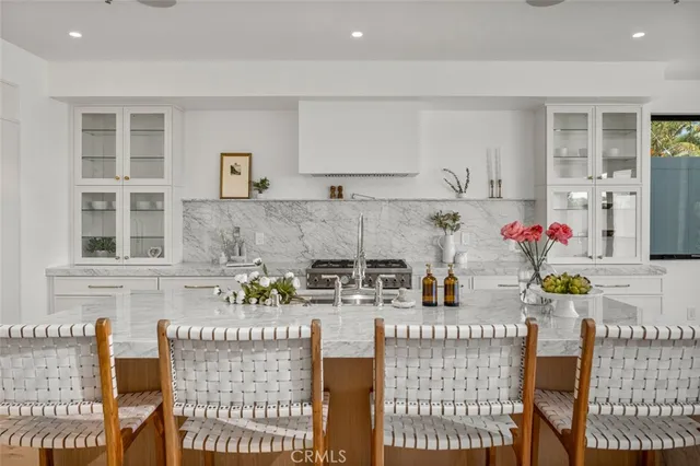 a view of kitchen with stainless steel appliances granite countertop dining table chairs cabinets and white countertops
