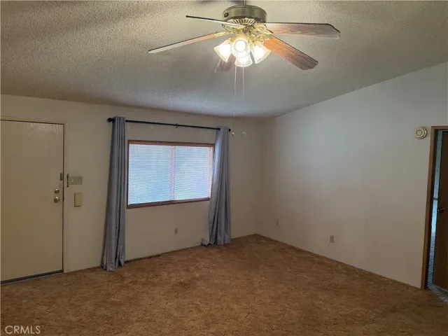 an empty room that has a chandelier fan and a window