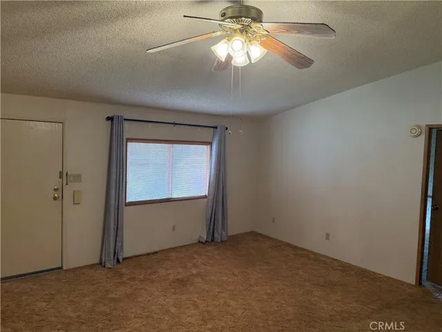 an empty room that has a chandelier fan and a window