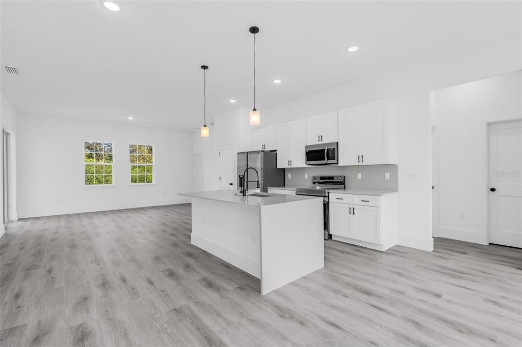 3428 Southwest 165th Loop Ocala, FL 34473 - Photo 15 of 43 a kitchen with stainless steel appliances granite countertop a stove a sink a microwave a center island and a wooden floor