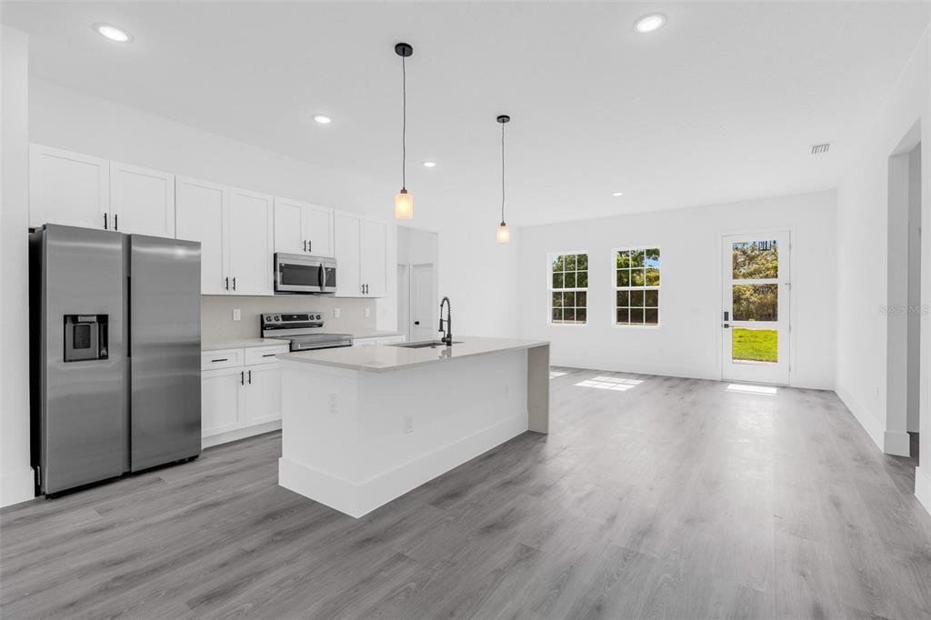 3428 Southwest 165th Loop Ocala, FL 34473 - Photo 8 of 43 a large kitchen with stainless steel appliances a large counter top a sink a refrigerator and a window