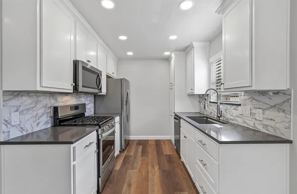 a kitchen with stainless steel appliances granite countertop a sink stove microwave and cabinets