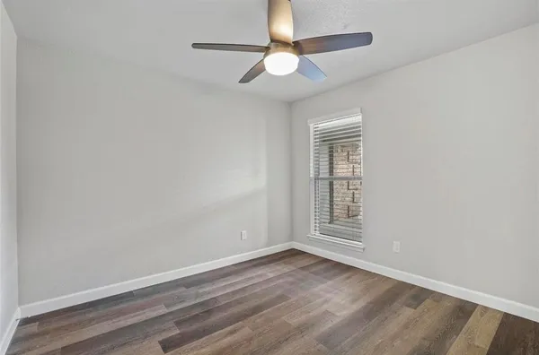 an empty room with wooden floor chandelier fan and windows