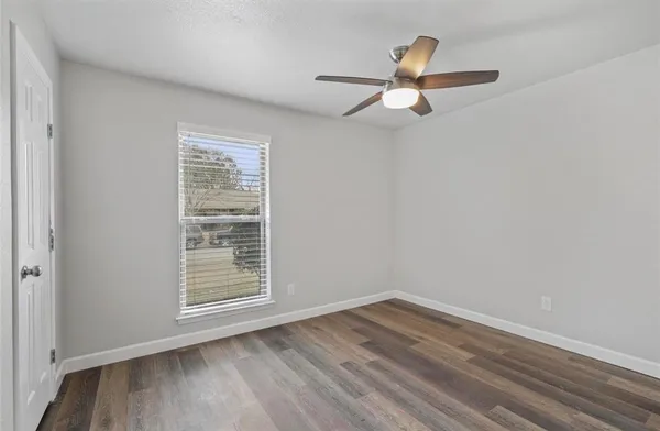 an empty room with wooden floor cabinet and windows