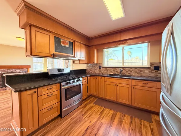 a kitchen with stainless steel appliances granite countertop wooden floor sink stove and granite counter top