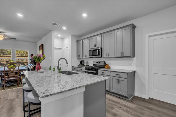 a kitchen with granite countertop a sink white cabinets and stainless steel appliances